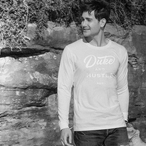 Joey wears The Flat White, white vinyl D&H logo on a white 100% cotton long sleeve unisex fit tee